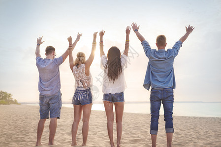 朋友们站在沙滩上背过身举手图片