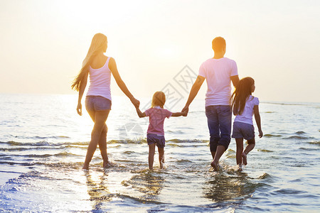 快乐的年轻家庭在日落时在海滩上奔跑玩得开心彩色照片图片