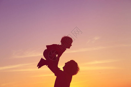 父亲和小儿子在日落的天边玩彩影图片