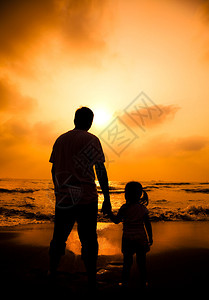 父亲牵着小女孩的手看海边日落图片