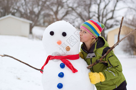 可爱的年轻女孩亲吻雪人她图片