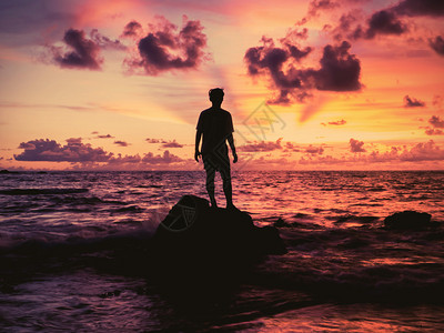 年轻人站在岩石上看日落图片