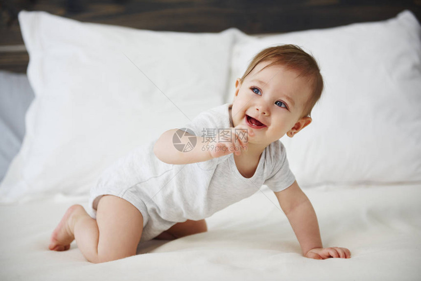 爬行在床上的愉快的婴孩图片