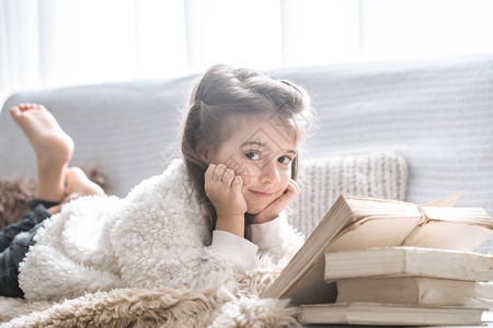 小女孩在舒适的客厅里读一本关于舒适沙发的书美丽的情感图片