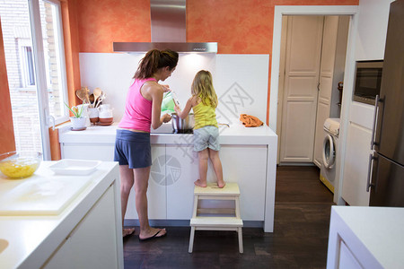 女人母亲和四岁的金发孩子的背影坐在厨房的梯子上图片