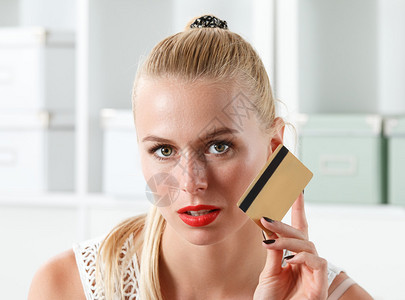 美丽的金发女人拿着金色的信用卡图片