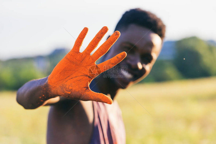 在霍利节用橙色涂料展示手势的非洲美国人有图片