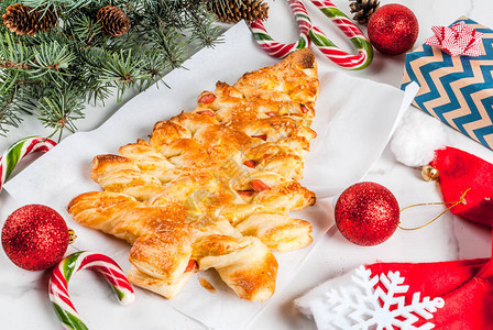 圣诞晚会的吃草包从松果糕饼中以圣诞树的形式关闭披萨在白大理石桌上带有图片