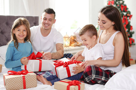 快乐的父母和孩子在家里圣诞节早上交换礼物图片