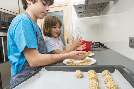小女孩和小男孩在里揉杏仁糖以制作小圆饼Panellet是AllSaints假期的传统甜点背景图片