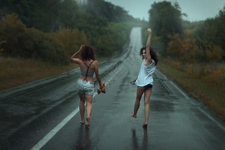 两个女孩在雨中的马路上图片