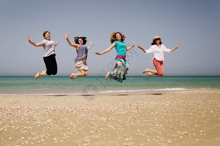 四位女性朋友在海边跳跃的照片图片