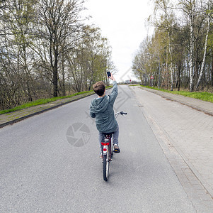 男孩在骑自行车时用机动车图片