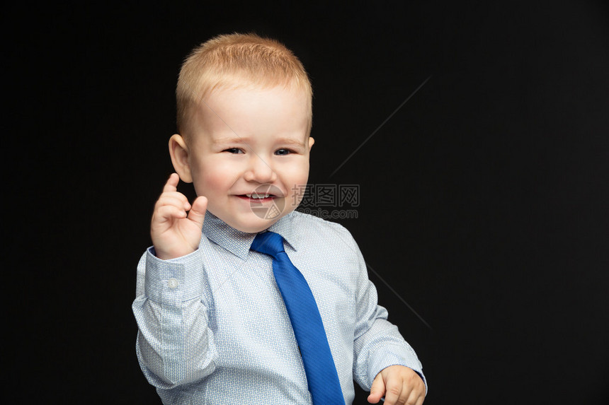 穿着衬衫背心和领带的可爱小男孩展示着一些小东西黑色背图片