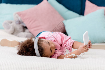 躺在床上听音乐用耳机在她的智能手机上监听音背景图片