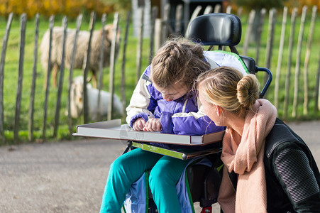 残疾儿童在轮椅上由一名护理助图片