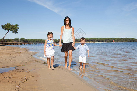 母亲牵着孩子们走在海边图片
