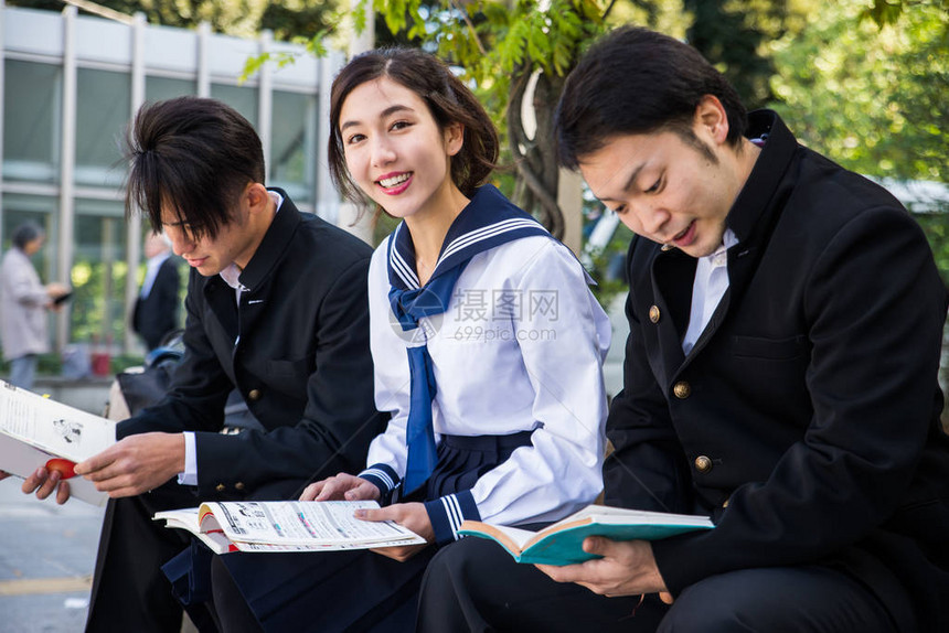 穿着校服的年轻日本学生在户外看书图片