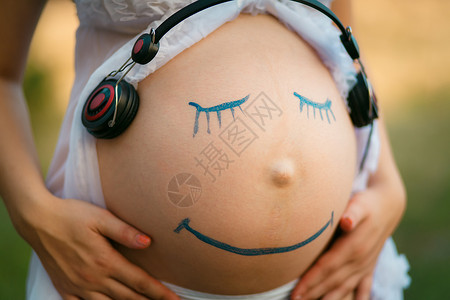 孕妇用微笑的脸闭着肚子图片