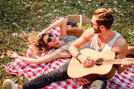 在野餐时向他的女孩弹吉他的男人图片