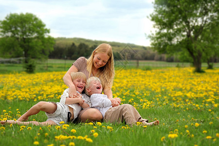一个快乐的年轻母亲和两个孩子一起在花棚里放松着笑图片