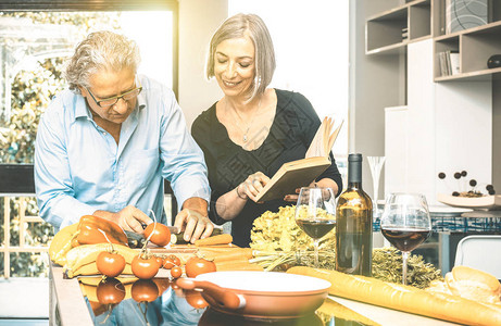 老夫妇在家厨房烹制健康食品和喝红酒退休人员在家准备午餐图片
