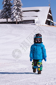 小男孩在山上雪行走与背图片