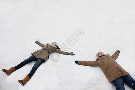 年轻夫妇躺在雪地里造雪天使图片