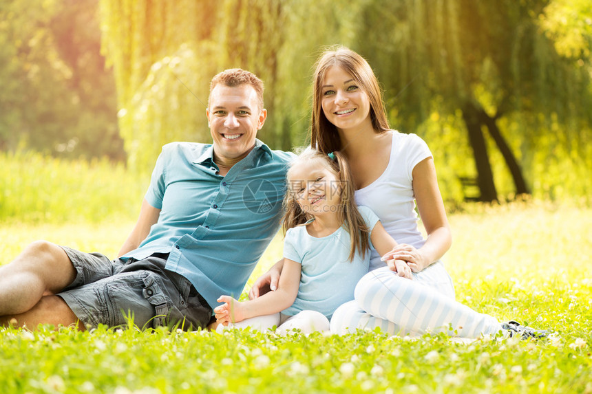 快乐的一家人坐在公园的草地上看图片