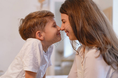 微笑的年轻母亲和学龄前儿子亲吻闭眼鼻子图片