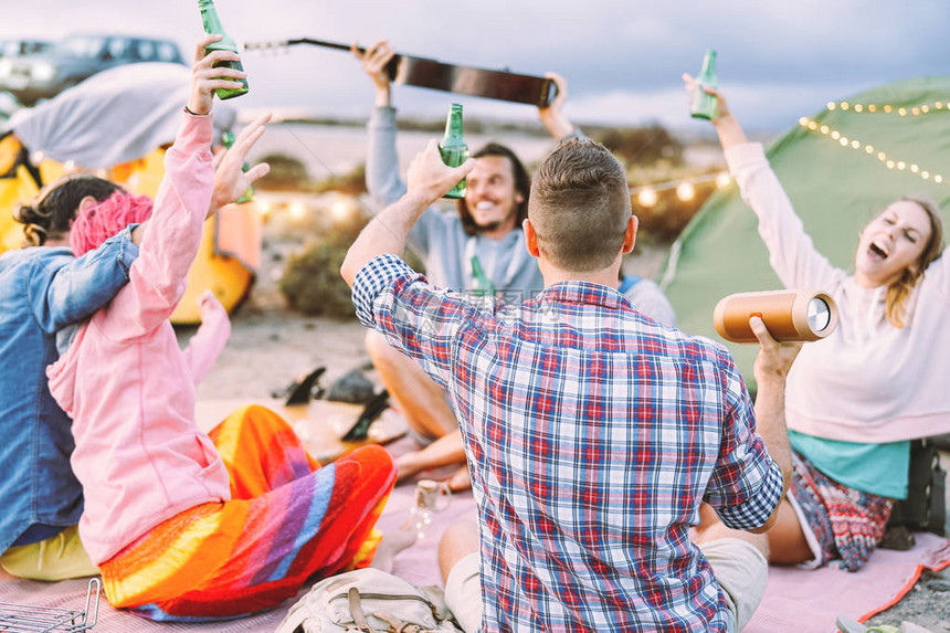 快乐的朋友在户外帐篷露营时开派对喝啤酒和演奏音乐图片
