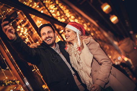 年轻快乐的情侣在圣诞节的夜晚自拍图片