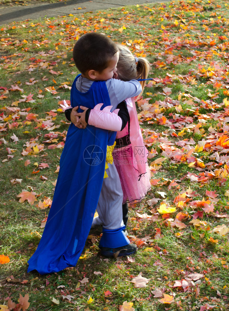 一个穿着服装的小女孩一个男孩穿着超级英雄服装和斗篷图片