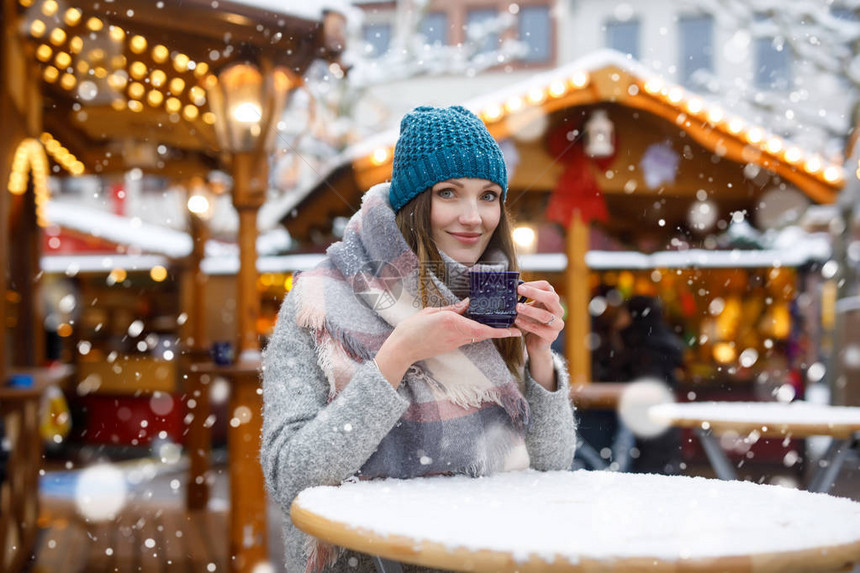 美丽的年轻女子在德国圣诞市场上喝着热潘趣酒甜酒德国汉堡冬雪日灯亮的图片