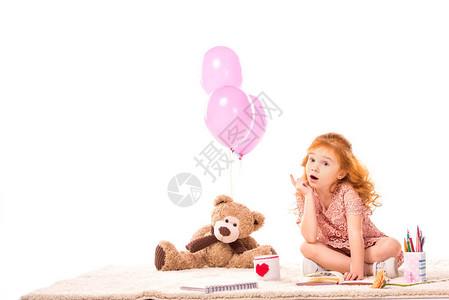 红发小孩坐在地毯上的玩具上在白色的图片