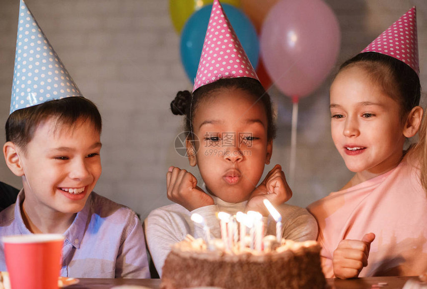 女孩在生日蛋糕上吹蜡烛许愿与朋友图片