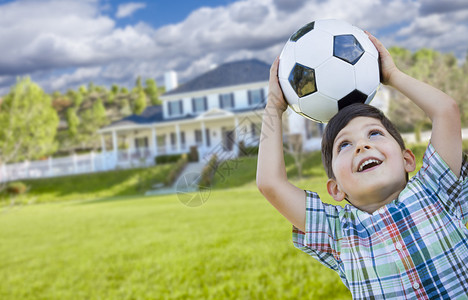 可爱的微笑年轻男孩拿着足球在美图片