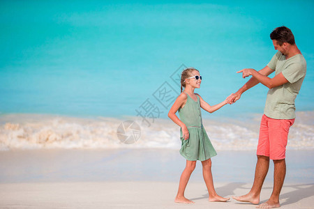快乐的父亲和他可爱的小女儿在热带海滩玩图片