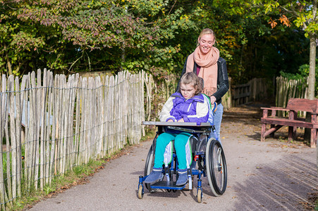 残疾儿童在轮椅上由一名护理助图片