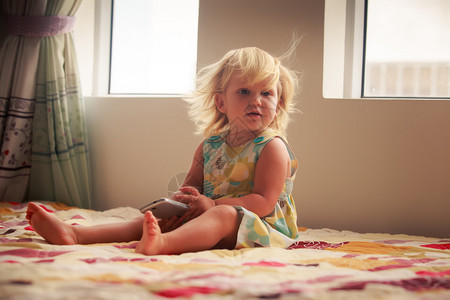 漂亮的小金发美女两岁的女孩玩智能手图片