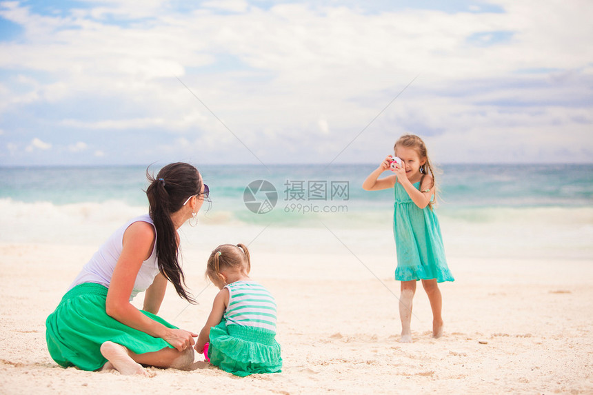 懂事的小女孩在沙滩上给妈妈和妹妹拍照片图片