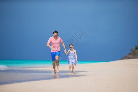 年轻父亲和小女孩在海边奔跑的家庭图片