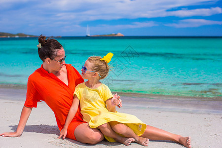 女孩和年轻母亲在沙漠岛屿热带海滩上玩得开心的幼图片