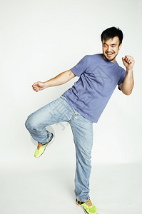 年轻漂亮的亚洲男人在白人背景下欢快地跳跃图片