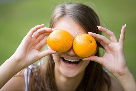 欢乐的姑娘的脸握着橙子在图片