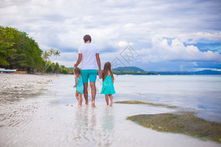 父亲和他的两个小女儿在海边散步的背影图片