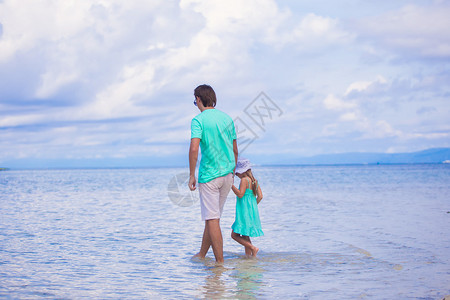 年轻父亲和他的小女孩在海边散步的背影图片