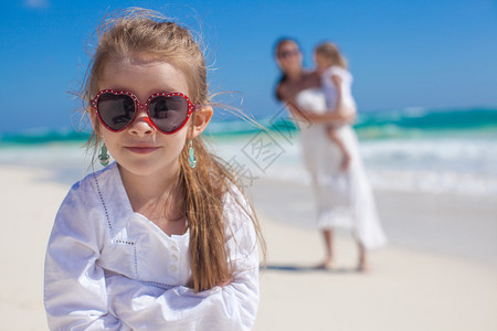 热带海滩背景中可爱的可爱女孩和她母亲与图片