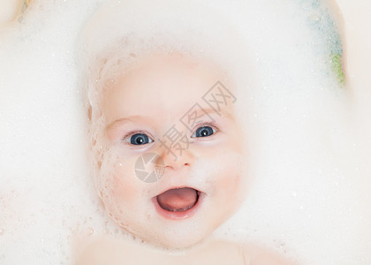 婴儿在有泡沫的浴缸里洗澡图片