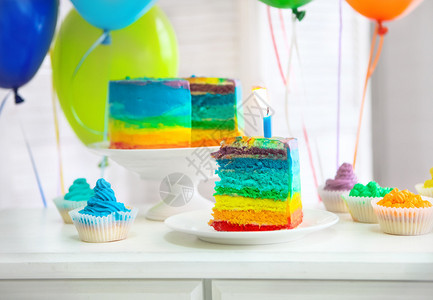 彩虹蛋糕和纸杯蛋糕配着生日蜡烛图片